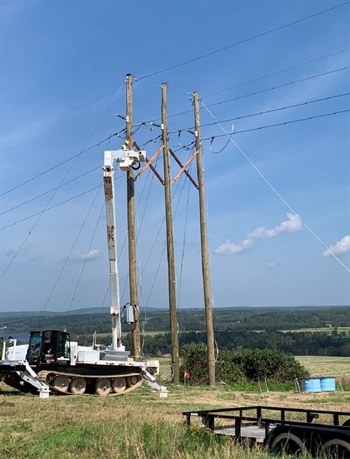  Crews use a tracked bucket truck to install X brace supports on the poles